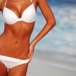 A woman's body wearing swimsuit on a beach after taking Body Lift